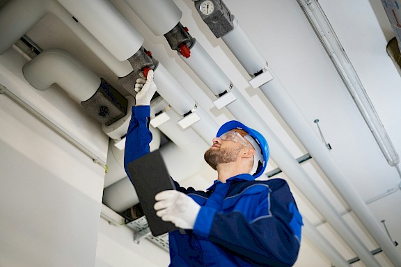 Techniker überprüft Heizungs- oder Rohrleitungssystem in einem Gebäude.